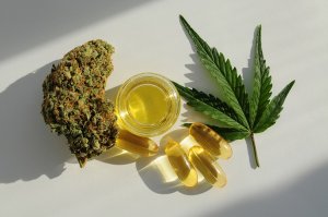 Sticks of technical cannabis next to a glass bottle of H4CBD distillate, cannabis capsules and a cannabis leaf