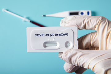 A gloved hand holding a covid-19 test kit